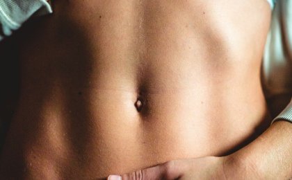 Hands resting on a flat stomach — symbolizing gut microbiome health, digestion, and core wellness