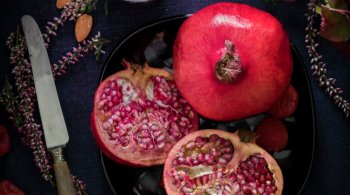 Seasonal superfoods including pomegranate, almonds, and berries on a dark plate