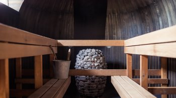 Interior of a traditional wooden sauna with hot stones and bucket for sauna therapy
