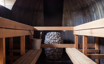 Interior of a traditional wooden sauna with hot stones and bucket for sauna therapy