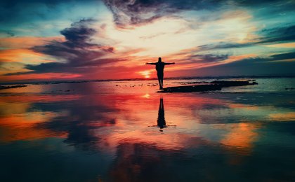 Silhouette of a person embracing the sunset on the beach, symbolizing freedom and vitality