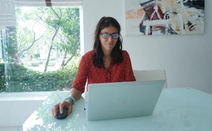 A woman in a red shirt sitting at her desk, focused on her computer while researching natural weight loss options.