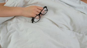 Young woman lying in bed with cold and tissue box, recovering during winter flu season