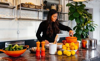 Woman cooking a meal in her kitchen, part of the regular-eating routine that helps regulate cortisol.