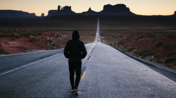 Person walking down a long road toward the horizon representing the journey of health optimization and long-term wellness