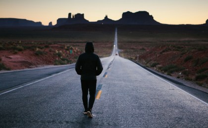 Person walking down a long road toward the horizon representing the journey of health optimization and long-term wellness