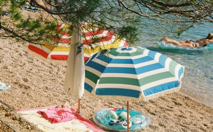 Beach umbrella and lounge chair on sunny shoreline — how to protect skin from sun damage naturally