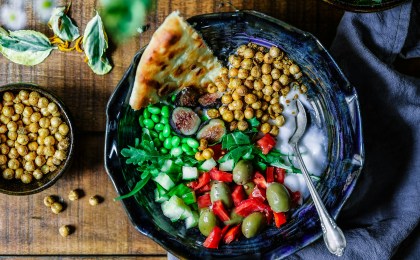 Colorful Mediterranean-style bowl with leafy greens, lean protein, whole grains, and healthy fats like olive oil